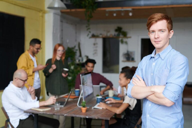 man standing beside people sitting beside table with laptops